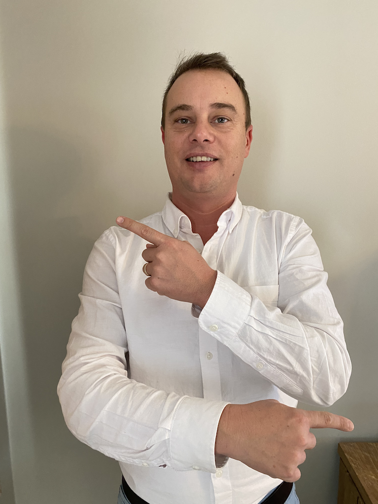 Een man in een wit overhemd wijst met zijn vinger.