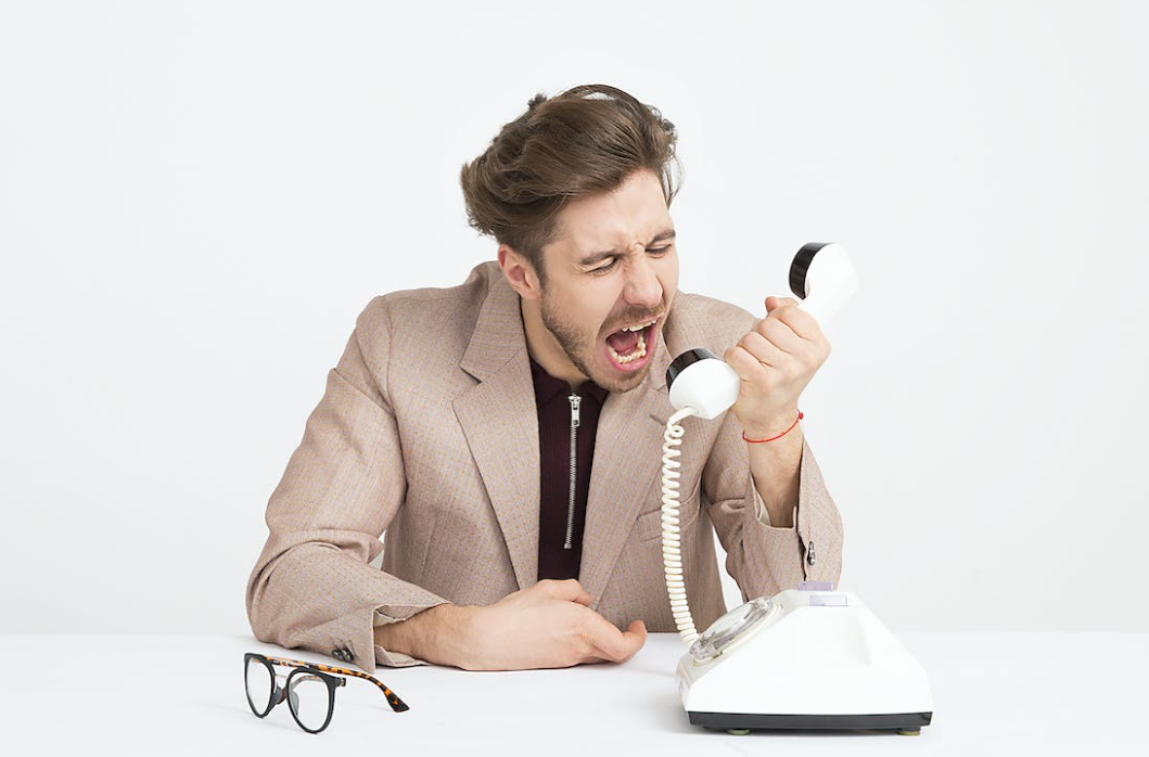 Een man die aan de telefoon schreeuwt terwijl hij als webdesigner werkt.