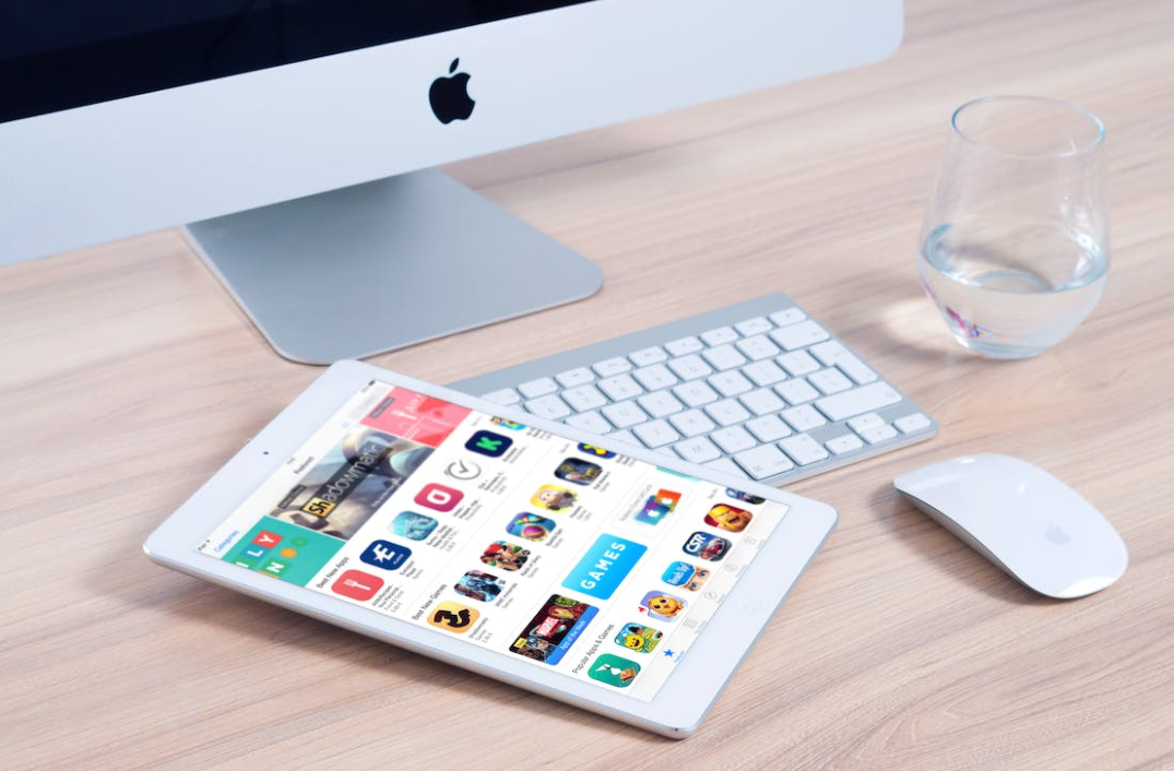 Een slanke Apple iPad met een prachtig responsief webontwerp wordt naast een muis en toetsenbord op een bureau geplaatst.