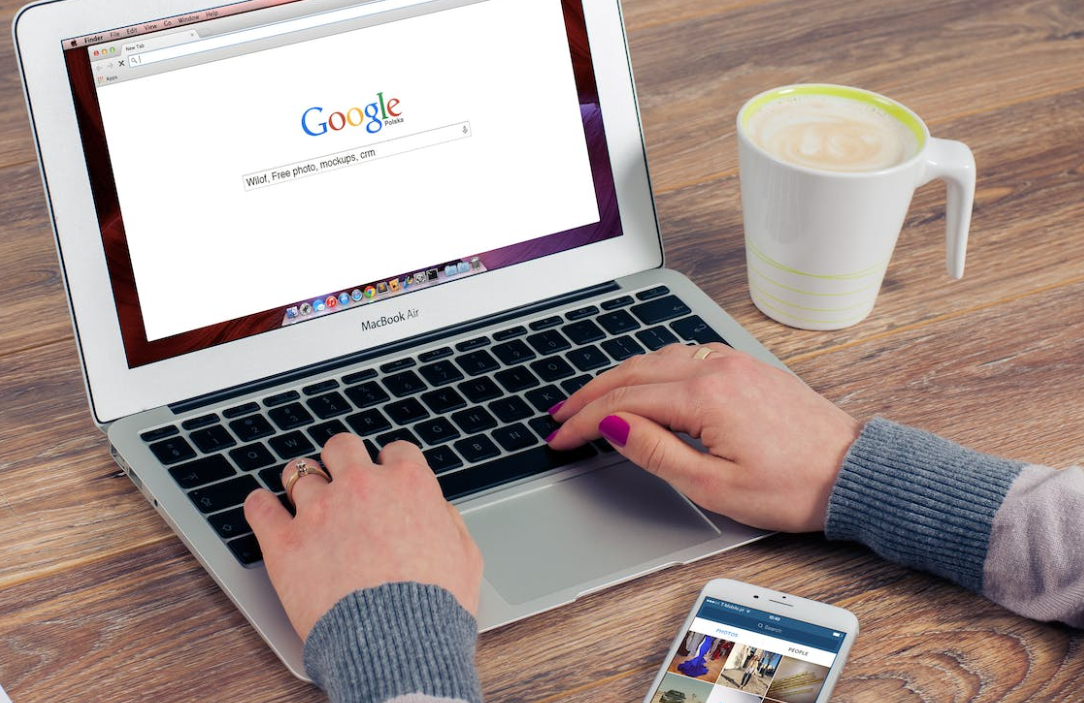 Een vrouw typt op een laptop met Google op het scherm.
