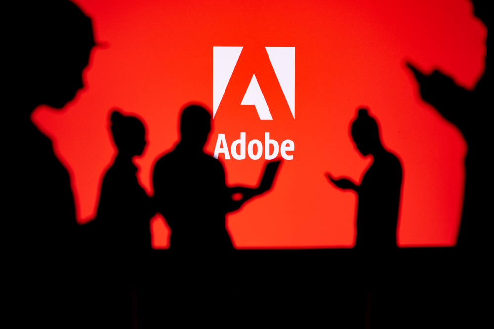 Indrukwekkende silhouetten van mensen die voor het Adobe-logo staan en hun expertise op het gebied van Adobe Creative Suite voor website-ontwerp demonstreren.